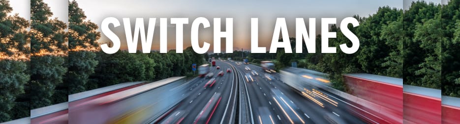 Multi-lane highway with blurred traffic moving at speed through a wooded area. At the top, the words: switch lanes.